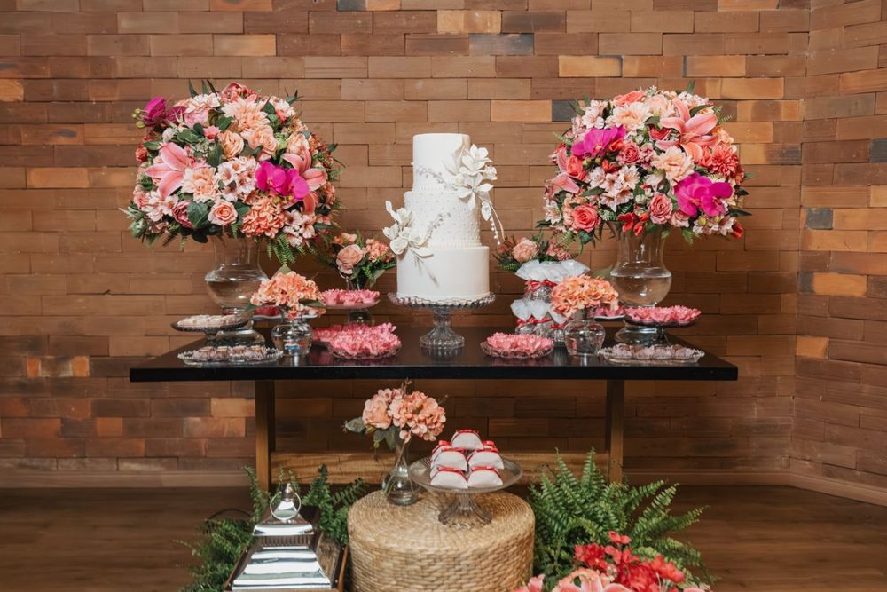 Dessert table with a white tiered cake and pink flowers