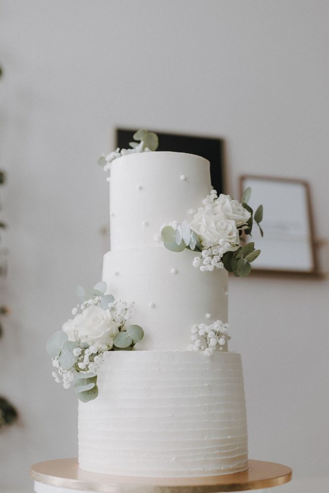 Three-tier white wedding cake with flowers